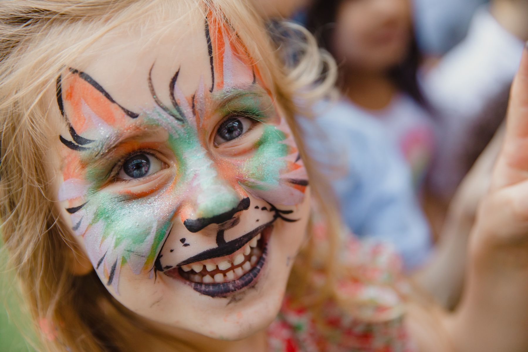 A smiling child with colorful face paint at a carnival