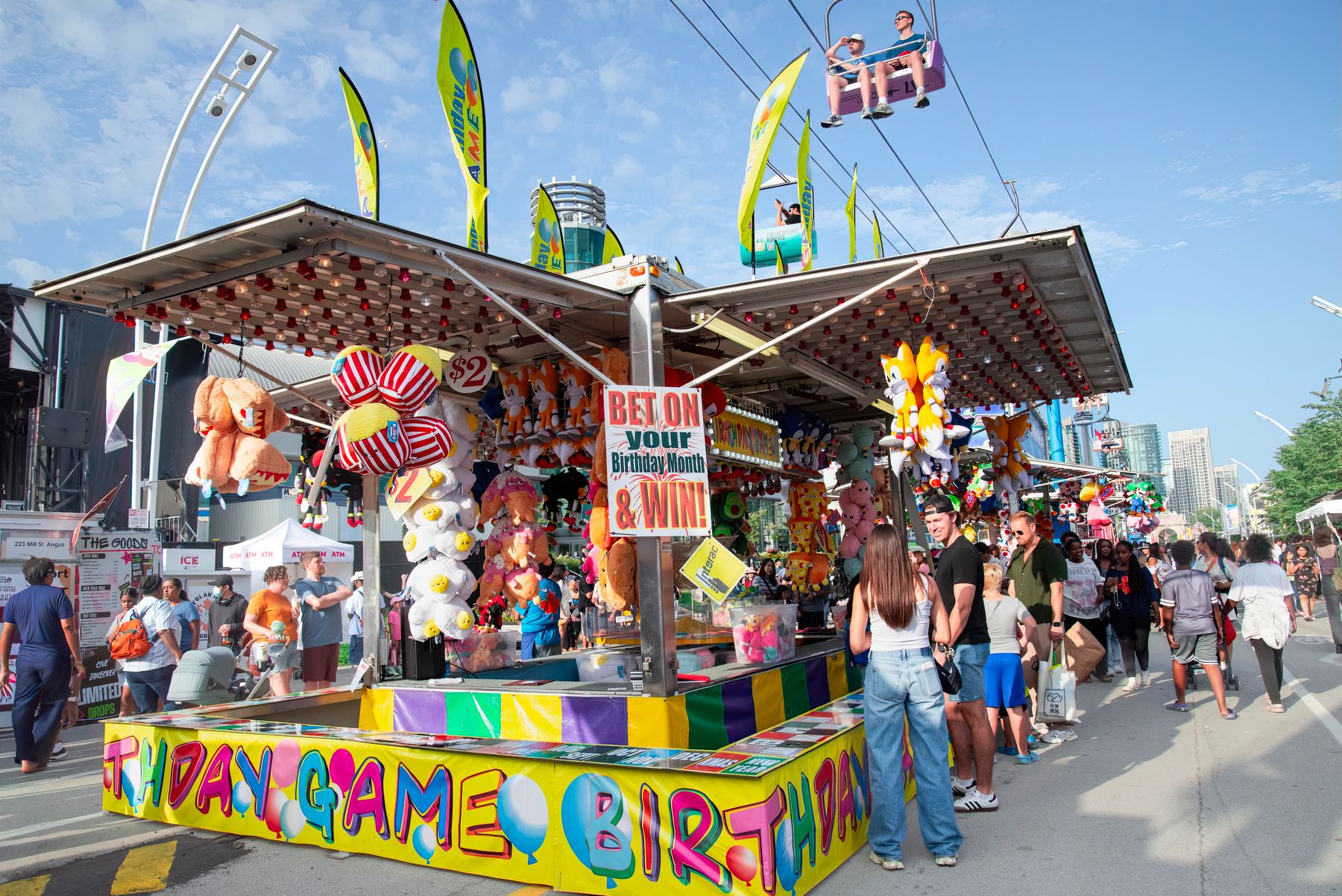 A row of colorful midway game booths at a busy fair