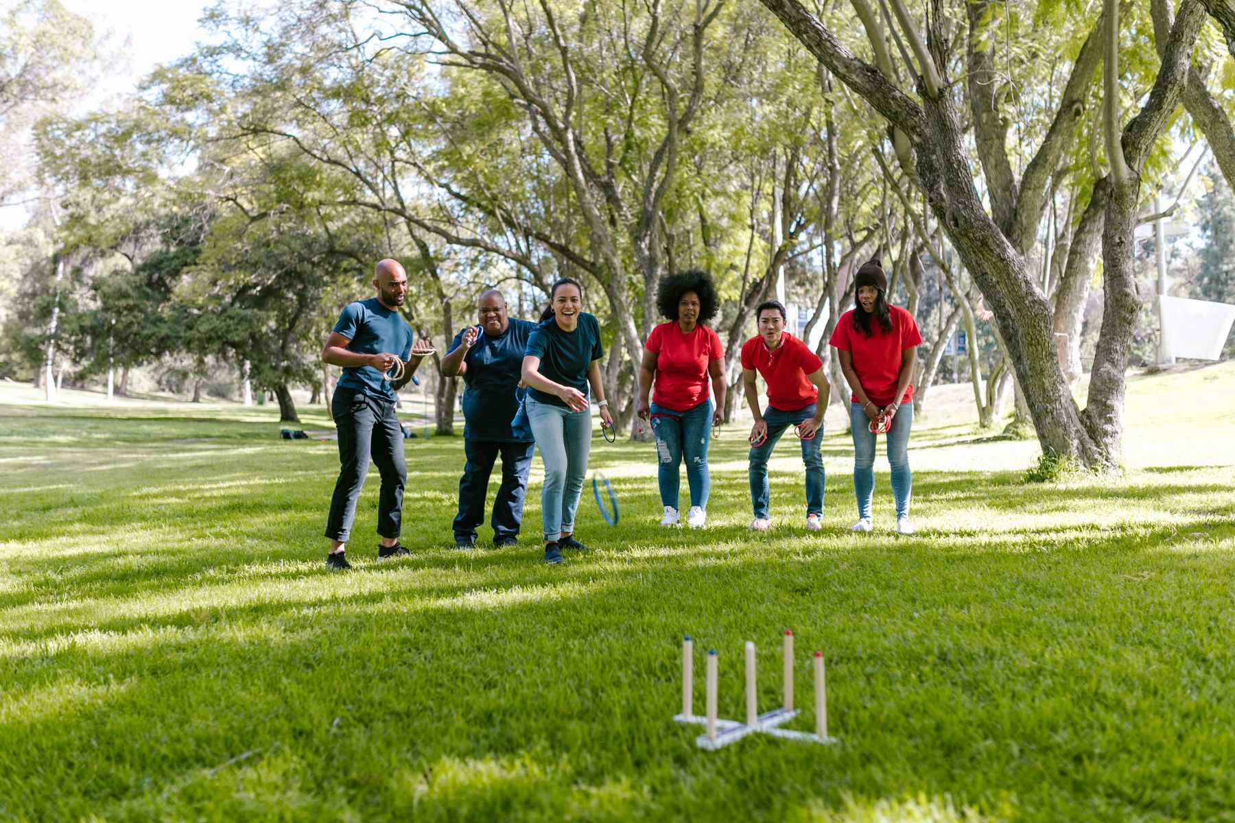 Friends playing a ring toss game on a park lawn