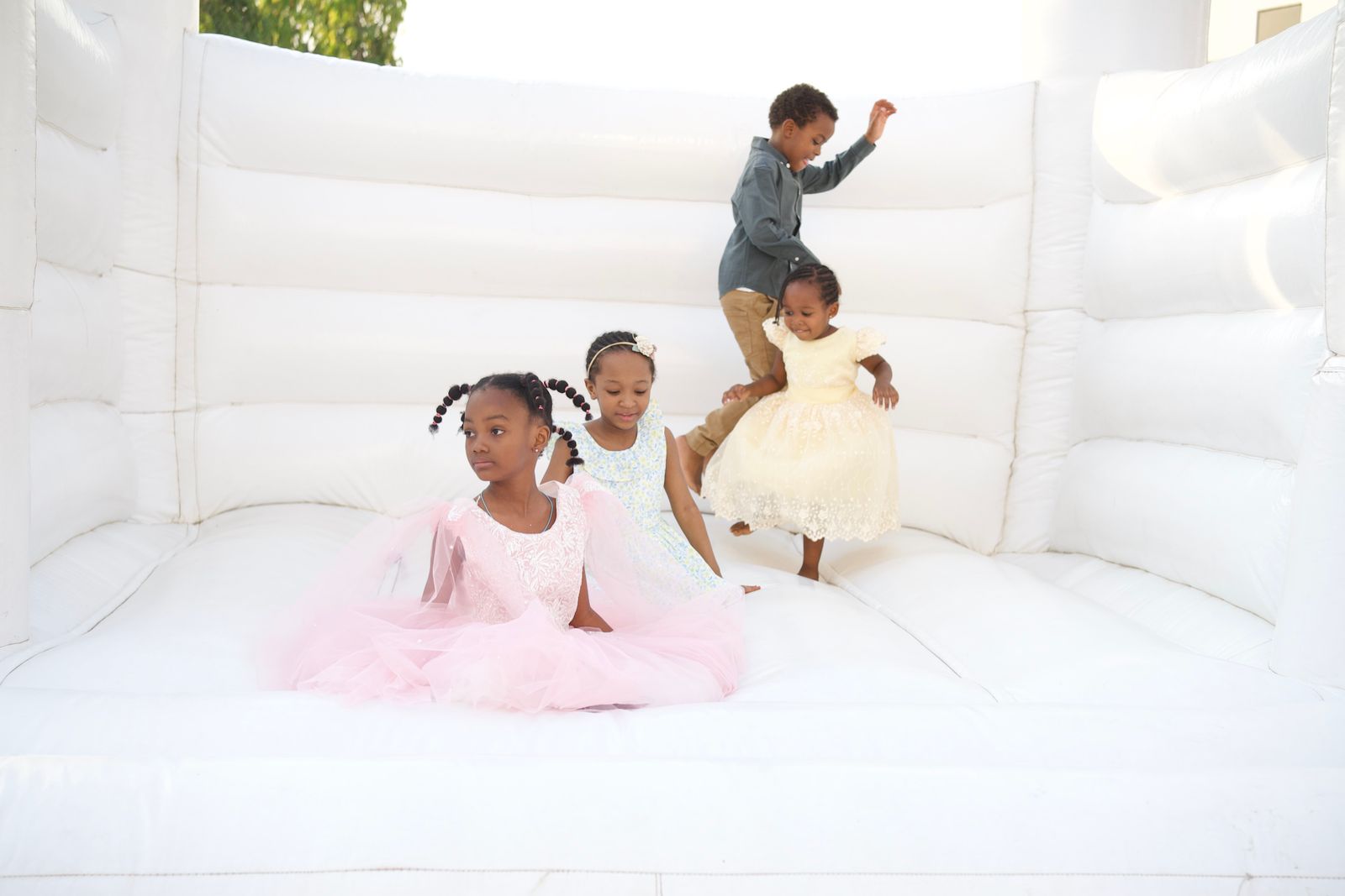 Kids in dressy party clothes in a white bounce house