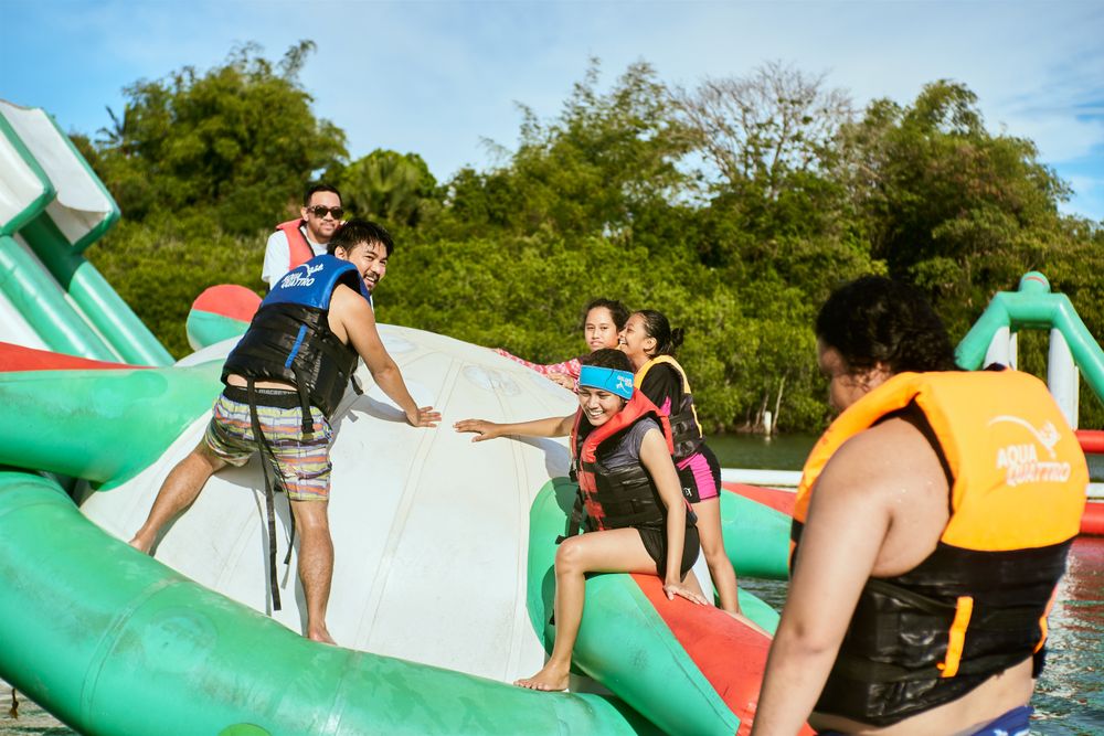 Kids in life jackets climbing out of an inflatable water attraction