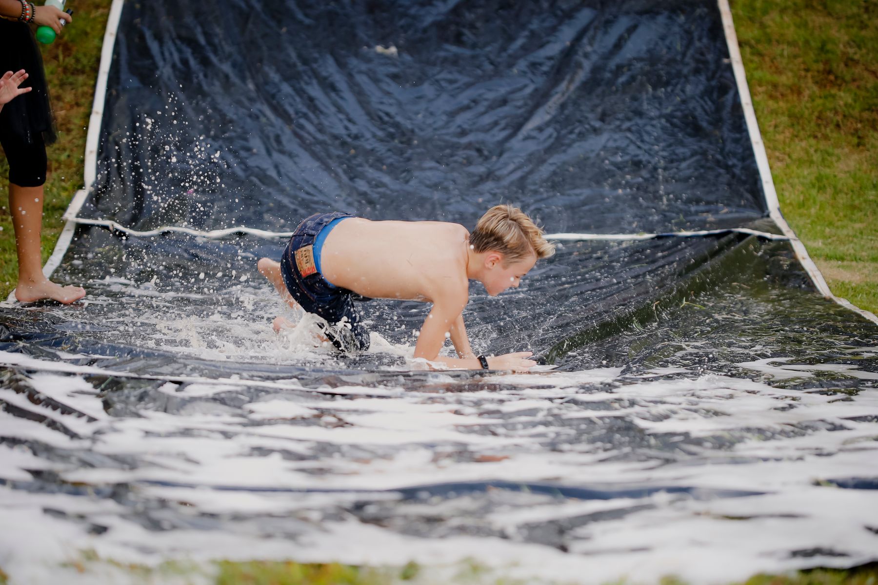 A child sliding down a soapy backyard slip-and-slide